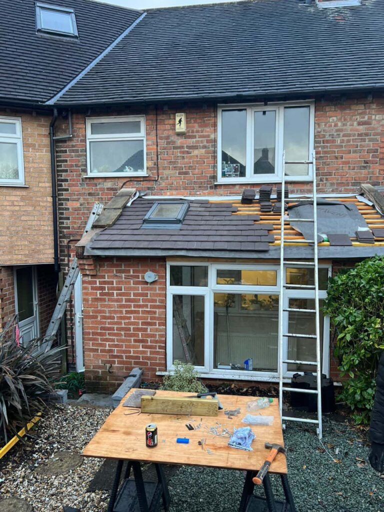 This is a photo of a roof extension that is having new roof tiles installed. This is a photo taken from the roof ridge looking down a tiled pitched roof on to a flat roof. Works carried out by Hurstpierpoint Roofing Repairs